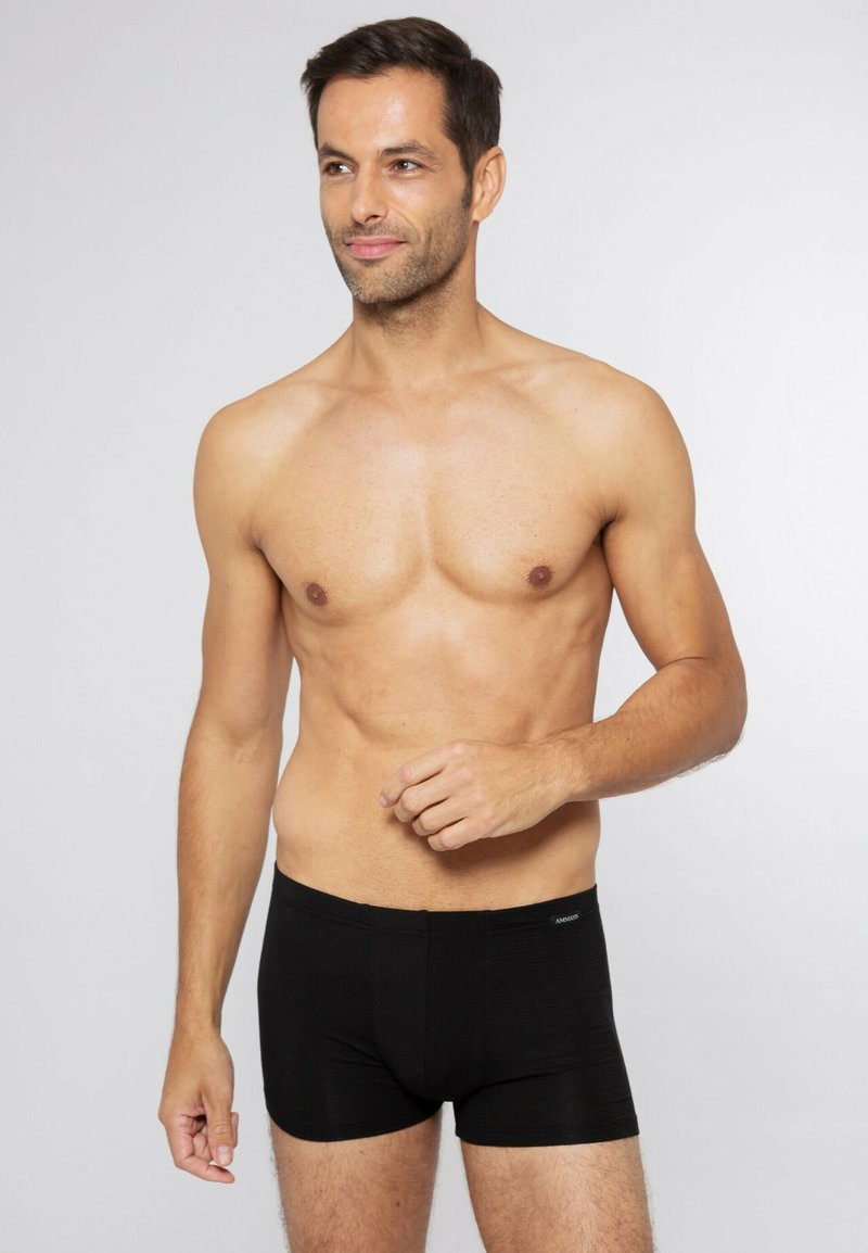 Boxer da uomo neri realizzati in tessuto elasticizzato, caratterizzati da un design aderente con una vita liscia e una texture sottile. Senza ulteriori motivi o dettagli.