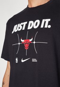 Melnas kokvilnas t-kreklis ar balto uzrakstu "TIKAI DARI TO." , sarkanu bull logo un NBA/Nike zīmolu tuvumā apakšmalai. Īsas piedurknes, apaļais kakls.