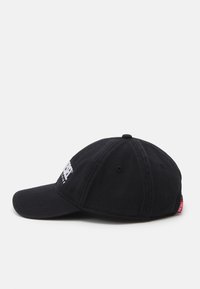 Fekete pamut baseball sapka ívelt csúccsal, fehér hímzett szöveggel az elülső részen és egy kis piros címkével az oldalán.