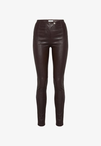 Ciemnobrązowe spodnie ze skóry z wysokim stanem, z przeszyciami z przodu oraz asymetrycznym zapięciem na guziki i zatrzaski w pasie.