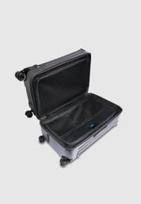 Hartschalen-Koffer in mattem Grau mit schwarzem Innenraum. Ausgestattet mit vier Rollen, Reißverschlussfächern und einem robusten Griff. Offen mit organisierter Aufteilung.
