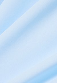 Tissu bleu clair avec une texture douce et lisse, présentant des plis diagonaux subtils qui créent des ombres et des reflets délicats.