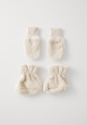 Beige wanten met een zachte, fluffy textuur. Ribgebreide manchetten aan de bovenkant en ronde uiteinden. Twee paar tentoongesteld, één plat en één gathered.