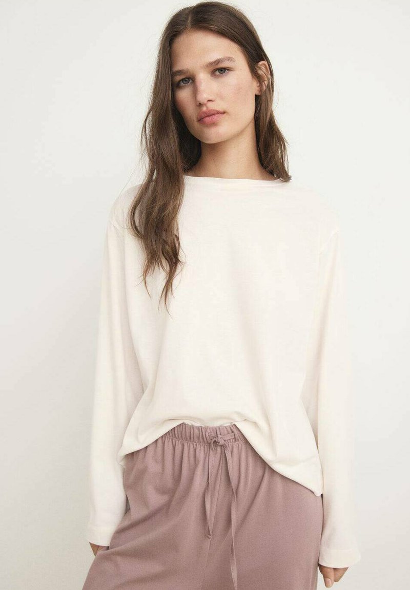 Maglia a manica lunga beige dal taglio morbido, abbinata a pantaloni rosa chiaro con vita regolabile. Design semplice con scollatura rotonda.