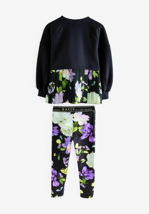 Sweat-shirt noir à manches longues avec un ourlet plissé floral, associé à des leggings ajustés ornés d'un mélange d'imprimés floraux colorés sur fond sombre.