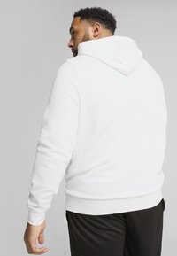 Sweatshirt alb cu glugă, realizat dintr-un material moale; are manșete și tiv ribbate; expus din spate cu un design minimalistic.