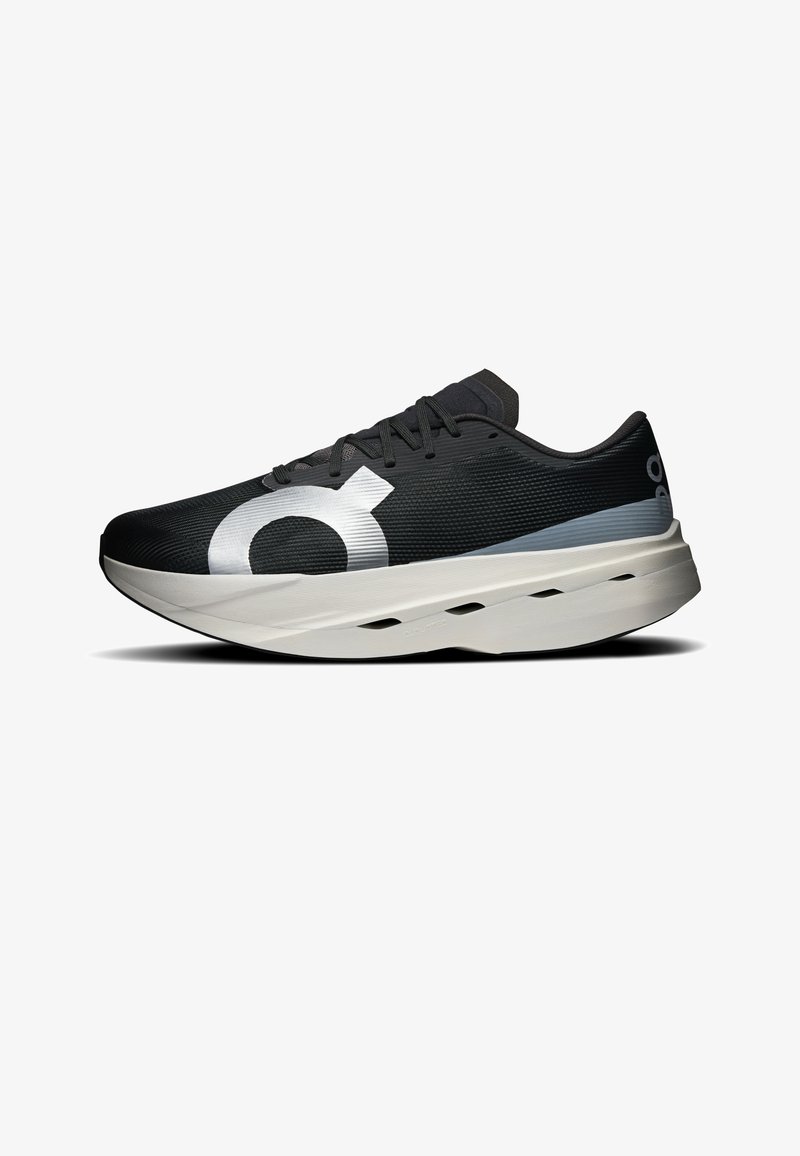 Chaussure de course noire avec grand logo circulaire blanc sur le côté, semelle épaisse blanche rembourrée avec des trous de ventilation et lacets noirs.