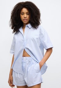 Μπλε και λευκό ριγέ πουκάμισο με κοντά μανίκια, κουμπώνει μπροστά, συνδυασμένο με σορτς που ταιριάζουν. Ελαφρύ ύφασμα με άνετη εφαρμογή.
