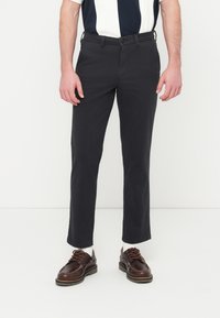 Chinos gris foncé à coupe slim, avec un design à plat à l'avant, des passants pour ceinture et une fermeture à un seul bouton, associés à des chaussures marron à lacets.