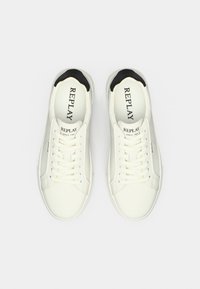 Λευκά δερμάτινα αθλητικά παπούτσια με στρογγυλεμένη μύτη, σχεδιασμό με κορδόνια και μαύρες λεπτομέρειες στον γιακά. Λογότυπο "REPLAY" εκτυπωμένο στο εσωτερικό του παπουτσιού.