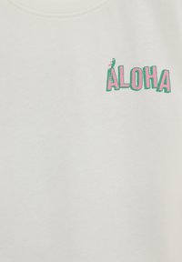 Tissu blanc avec le texte rose et vert "ALOHA", avec un petit oiseau vert perché sur la lettre A dans le coin supérieur gauche.