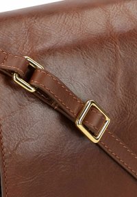 Borsa a spalla in pelle marrone con superficie testurizzata, dotata di una fibbia quadrata dorata e cuciture lungo la tracolla.