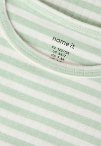 Bawełniana koszula w zielono-białe paski z okrągłym dekoltem. Charakteryzuje się miękką fakturą i zawiera metki z rozmiarem ubrania w pobliżu dekoltu.