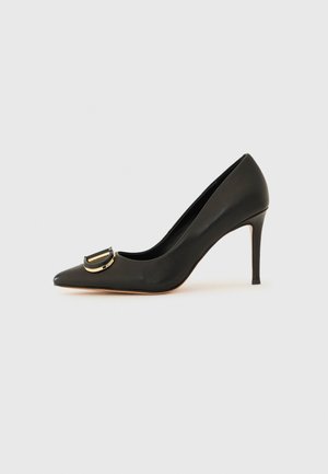 Must kuldast nahk pump, millel on terav varvas ja goldist ümmargune pandla detail peal, ning õhuke stilettokonts.