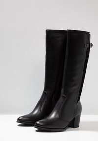 Czarne, wysokie do kolan botki wykonane z gładkiej skóry, z okrągłym noskiem, słupkowym obcasem oraz bocznym zamkiem błyskawicznym z małym ozdobnym paskiem.