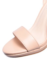 Sandal con tacco alto beige caratterizzata da una fascia ampia sulla punta, materiale sintetico liscio, punta arrotondata e una leggera lucentezza.