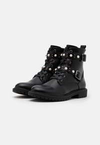 Bottines en cuir noir avec des accents de sangle et de boucle, ornées de clous en métal et de perles, dotées d'une semelle texturée pour une meilleure adhérence.