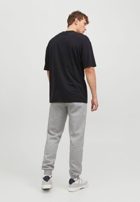 Black cotton t-shirt paired with gray sweatpants. Slim fit, subtle texture, and a clean design with ribbed cuffs. White sneakers complete the look.