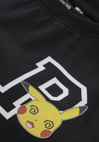 Czarna bawełniana koszulka z dużą, kolorową grafiką Pikachu z spiralnymi oczami i czerwoną policzkiem, obok odważnego białego napisu "P".