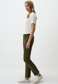 Olijfgroene rechte broek van een katoenmix, gecombineerd met een witte T-shirt met korte mouwen en witte sneakers. Gladde textuur, zonder patronen.