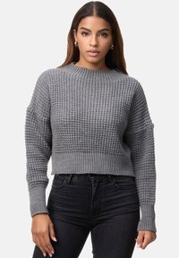 Grå strikket trøje med et tekstureret mønster, rund halsudskæring, cropped design og lange ærmer, kombineret med sorte jeans med høj talje.