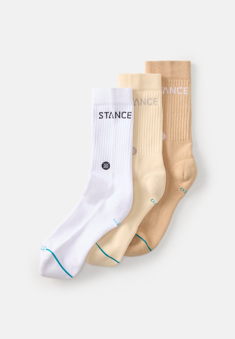 Trois paires de chaussettes : blanches, beige clair et brunes. Chaque chaussette présente une texture côtelée, un logo et des accents de couleur contrastante au niveau des orteils et du bord.