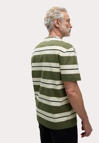Krátký rukáv, pruhované tričko v olivově zelené a krémové barvě, s černými akcenty. Měkká látka, volný střih, s kulatým výstřihem.