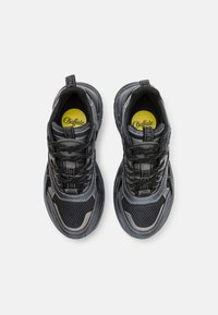 Black mesh sneakers with reflective accents, textured overlays, and a logoed insole. Features elastic laces and padded collar.
