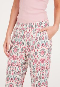 Geprinte broek met een lichtcrème achtergrond, featuring een mix van rode, grijze en turquoise diamant- en abstracte vormen; met zijzakken.