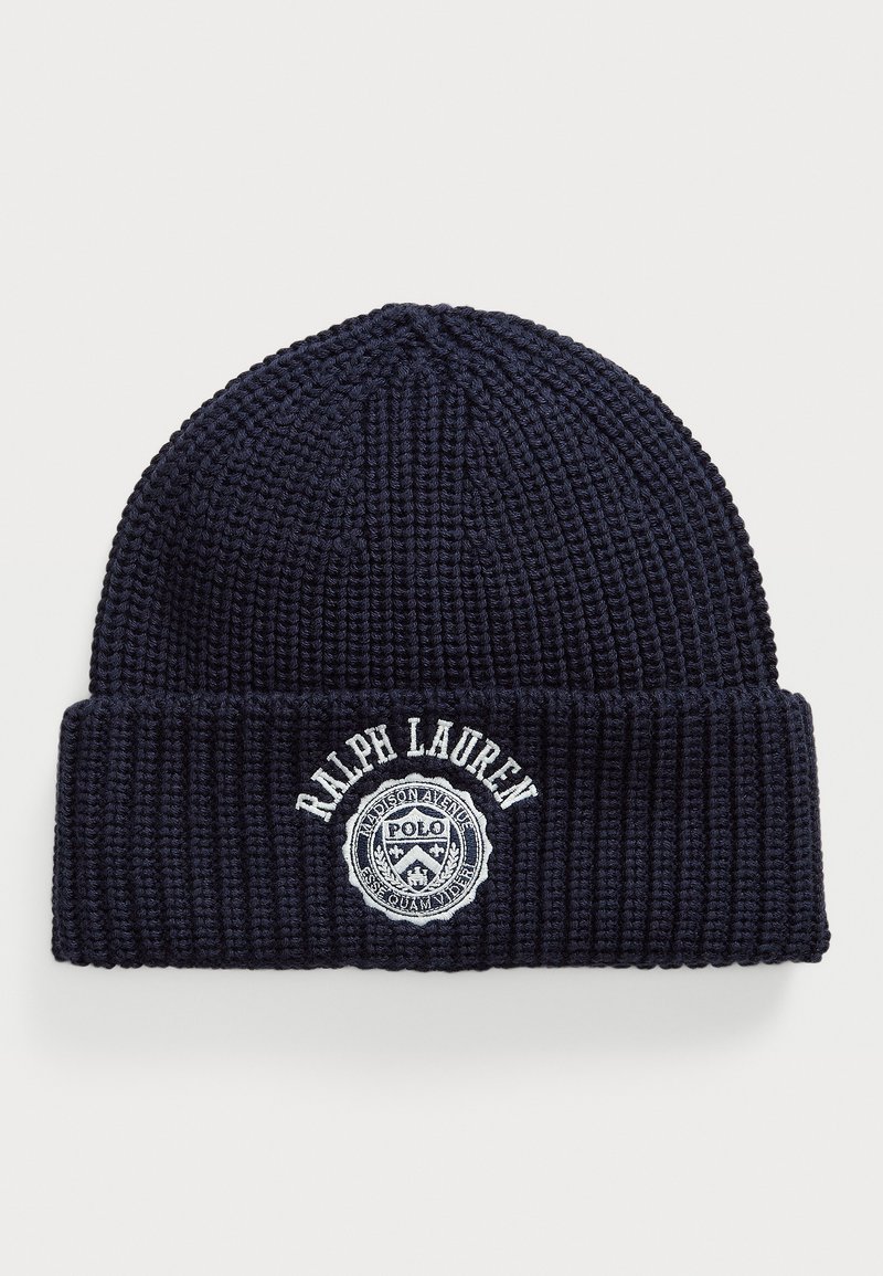 Tengerészkék bordázott kötött sapka hajtott fodrával, amelyen fehér hímzett "Ralph Lauren" felirat és egy kör alakú Polo logó címke található.