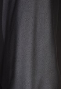 Černá látka s hladkým povrchem a mírným leskem, vyznačující se minimalistickým designem a jemným splýváním. Vhodná pro různé oděvy.