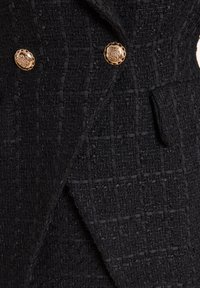 Zwarte tweedjacket met een textuurstof, met een dubbelbreasted ontwerp en twee goudkleurige knopen als accenten.