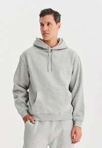 Szara, hoodie wykonana z miękkiego materiału. Posiada kieszeń kangurka i ściągacze na mankietach, luźny krój oraz kaptur ze sznurkiem.