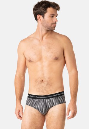 Culottes à motifs noirs et blancs avec une ceinture élastique noire portant le nom de la marque. Le tissu semble doux et ajusté.