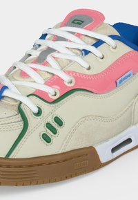 Αθλητικό παπούτσι σε κρεμ, ροζ και μπλε χρώμα με λευκά κορδόνια, πράσινες λεπτομέρειες, καφέ σόλα και λογότυπο "globe" στο πλάι και στη σόλα.