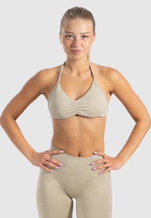 Beige halter-bikinitop met plooidetails, gecombineerd met bijpassende hoge taille leggings. Glad, rekbaar materiaal met minimale hardware.