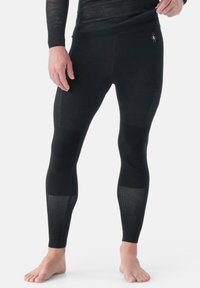 Zwarte lange leggings van een lichtgewicht, rekbaar materiaal met gestructureerde netpanelen bij de knieën en kuiten voor ademend vermogen.