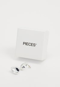 Sidabrinės metalinės auskarų kištukai organiškai formuoti, su aukšto blizgesio apdaila. Pateikti baltoje dėžutėje su užrašu "PIECES."