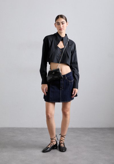 Black cropped shirt with pointed collar, button detail; worn with a denim mini skirt and black lace-up flats. Accessories include a black handbag.