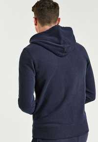 Marineblaues Hoodie aus weichem Stoff, mit einer Kapuze mit Kordelzug, gerippten Bündchen und Saum, weichem Griff und lässiger Passform.
