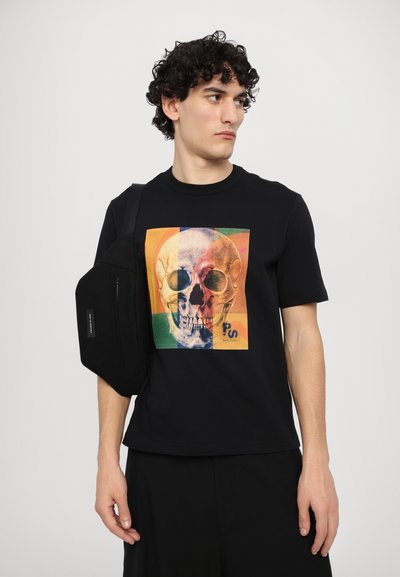 Black t-shirt featuring a colorful skull graphic on the front, paired with a compact black shoulder bag. Simple, modern design.