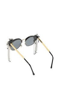 Kattögon-solglasögon med svarta bågar, grå linser, gyllene armar och silverpärlfransdetaljer längs den övre kanten för extra textur.