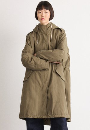 Ελαιόχρωμο παρκά με κουκούλα, κούμπωμα με κουμπιά και πλαϊνές τσέπες. Διαθέτει ρυθμιζόμενα κορδόνια και χαλαρή εφαρμογή.