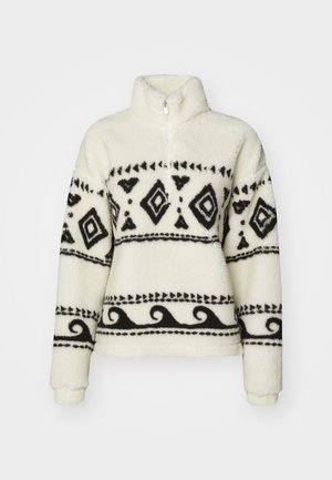 Pull en polaire crème avec des motifs géométriques et en vagues noirs ; il dispose d'un col zippé mi-haut et d'une coupe semi-ample, avec une texture douce.