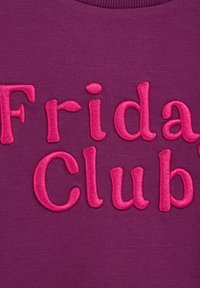 Fialová látka s ružovo vyšívaným textom "Piatkový klub". Písmená majú textúrovaný, zvýraznený vzhľad.