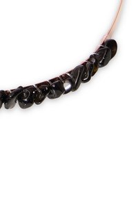 Czarny naszyjnik z kamieni o nieregularnych kształtach, nawleczony na cienki, elastyczny drut. Błyszcząca powierzchnia i gładka faktura.