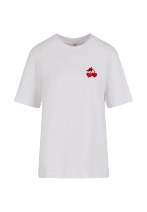 Valkoinen puuvillapaita, jossa on punainen brodeerattu kirsikkakuva vasemmassa rinnassa. Lyhyet hihat ja klassinen pyöreä pääntie.