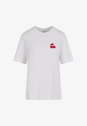 Valkoinen puuvillapaita, jossa on punainen brodeerattu kirsikkakuva vasemmassa rinnassa. Lyhyet hihat ja klassinen pyöreä pääntie.