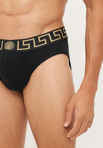 Slip en coton noir avec une large ceinture à motif en or et noir de clé grecque. Présente un logo rond au centre de la ceinture.
