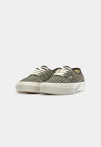 Sneakers met een geweven dambordpatroon in groen en zwart, met crèmekleurige veters, een witte rubberen zool en een lage stijl.